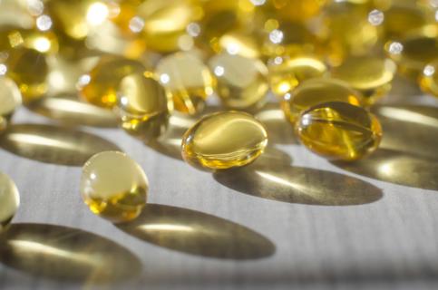 Vitamin D supplement capsules scattered in the sunlight on a table