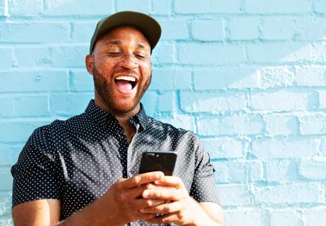 man laughing at text on smartphone