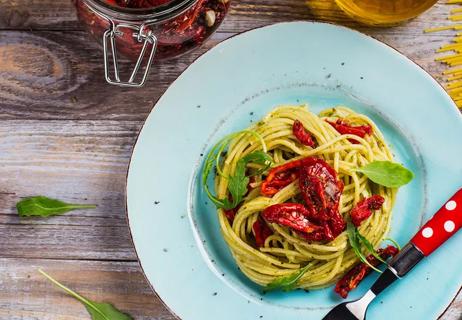 Linguine with garlic, oven-roasted tomatoes and arugula on a blue plate.