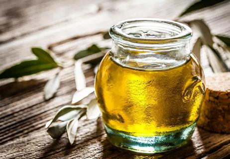 Small jar of olive oil on a rustic wooden table.