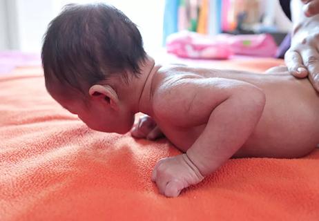 A baby doing tummy time on an orange blanket