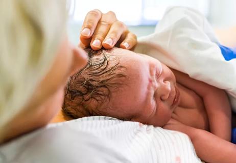 Mom cuddling newborn baby right after birth