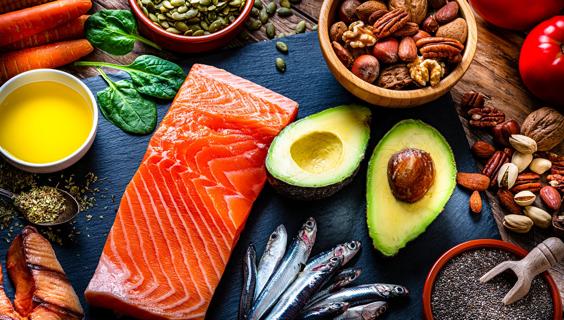 Assorted heart-healthy foods, like salmon, sardines, avocado, walnuts and seeds