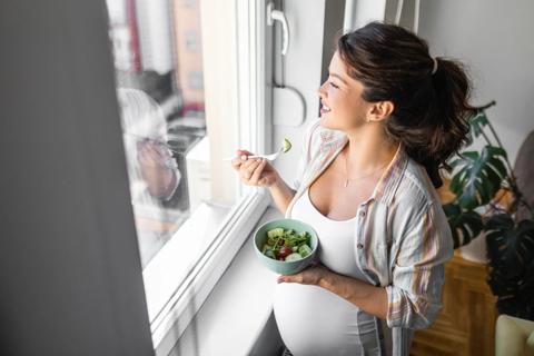 Pregnant woman eating bowl of salad