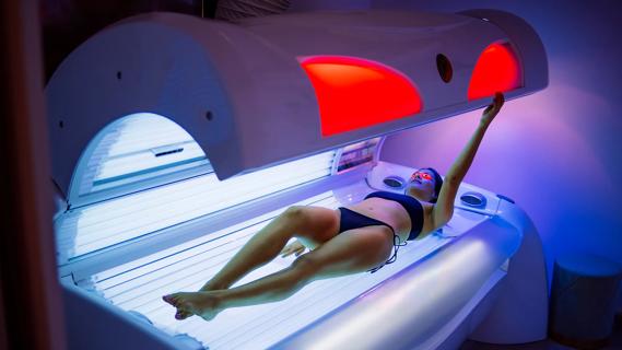 Person lying in tanning bed, closing it