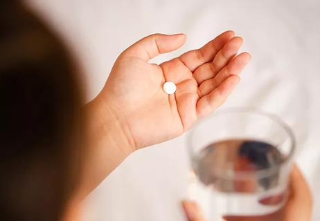 Close up of the one round white pill in female hand.