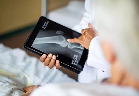 A person pointing to an X-ray of a bone on their tablet