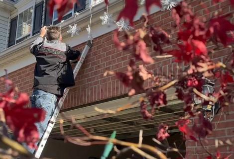 Man on ladder decorating house