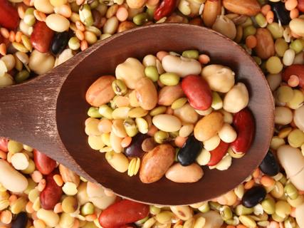 Big wooden serving spoon filled with assorted beans and legumes