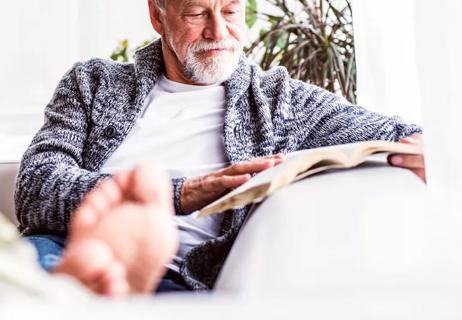 Elderly man with feet up on couch