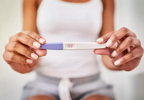 Woman holding positive pregnancy test stick