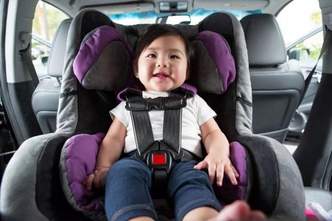 Older child belted into rear-facing care seat, in back seat of the car