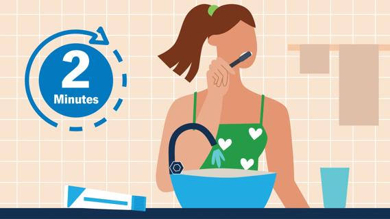 Person brushing their teeth at the bathroom sink, with oversized timer set for two minutes