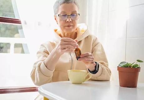 person reading a CBD oil bottle with cup of tea