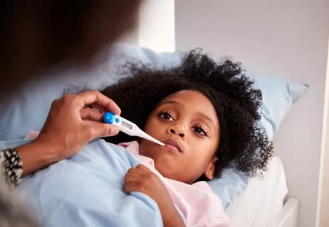 Person taking electronic temperature of sick child in bed.