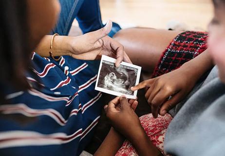 two people looking at a printed sonogram picture of a fetus