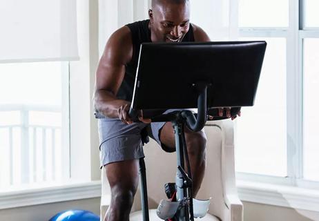 Sweaty, muscular individual in workout gear rides a stationary spinning bike