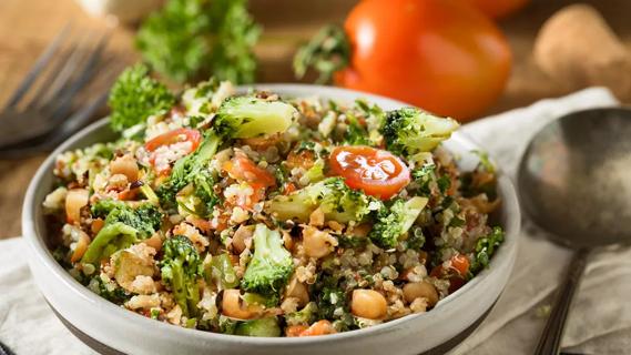 Charred broccoli tossed with cherry tomatoes, cucumbers, chickpeas and cooked bulgar wheat in a bowl