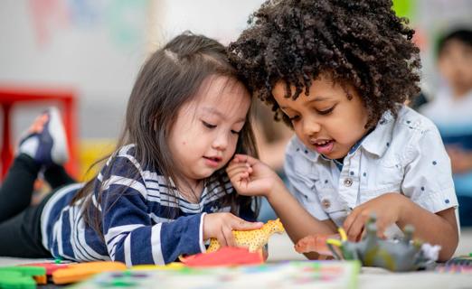 Children in kindergarten playing and sharing toys