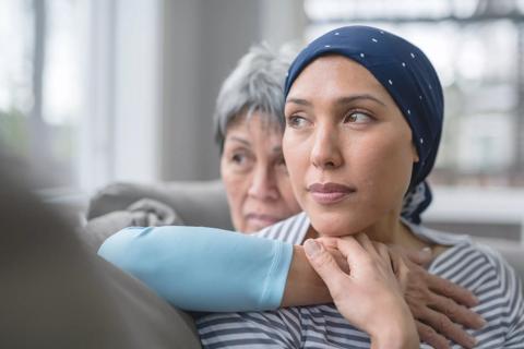 Female wearing bandana on head being embraced by family member