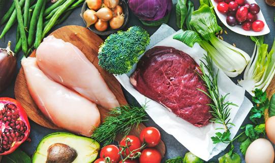 Raw chicken and steak among fruits, vegetables and eggs