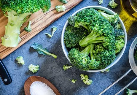 A bowl of broccoli from above sitting on a blue marble countertop.