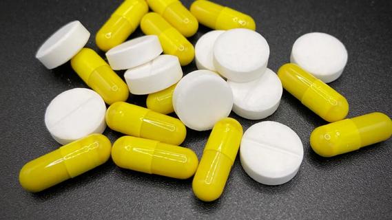 yellow and white pills strewn on a dark countertop