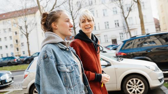 Parent and teen walking and talking down the sidewalk