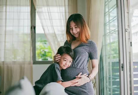 A child hugging a pregnant person