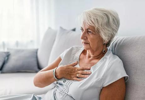 Concerned individual sitting on a couch with their hand to their chest