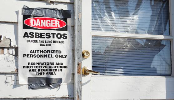 Asbestos warning sign taped to side of house