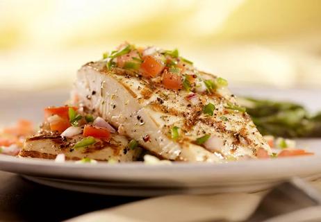 Grilled halibut on a plate topped with herbs and vegetables