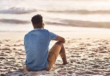 Person sitting on beach near water.