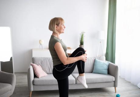 Older person standing, doing stretches in their living room