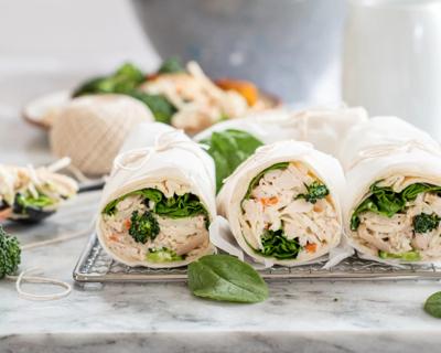 Broccoli slaw chicken wraps wrapped in paper, tied with string on cooling rack on counter