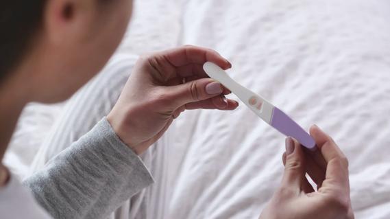 Woman looking at positive pregnancy test stick