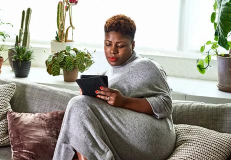 woman relaxing at home and reading on tablet