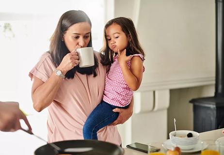 Adult sipping coffee while holding a child