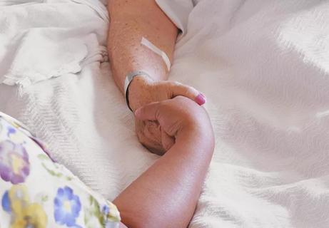 Nurse holding senior patient&#8217;s hand, close-up of hands