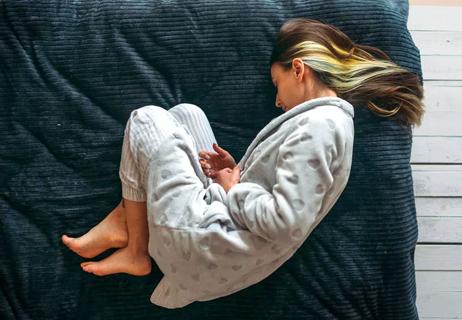 Woman in pain lying on a futon