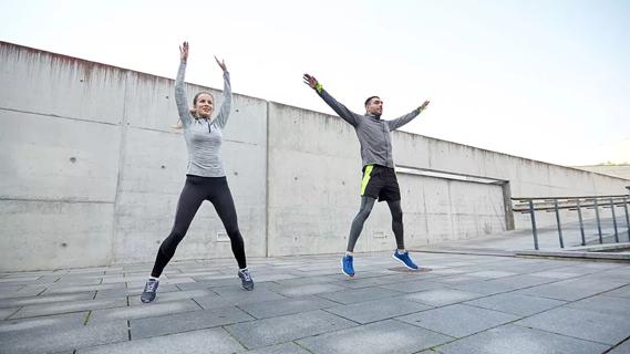 two people doing jumping jacks on pavement outside