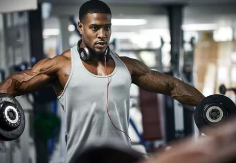 Person lifting handweights while looking into the mirror at the gym.