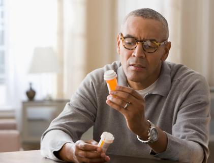 Person holding two prescription medicine bottles, comparing info