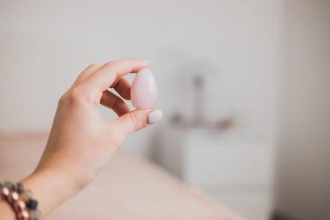 Hand holding up a pink yoni egg