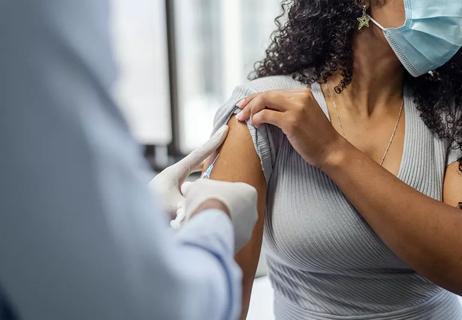 Masked person receiving vaccine shot in their shoulder