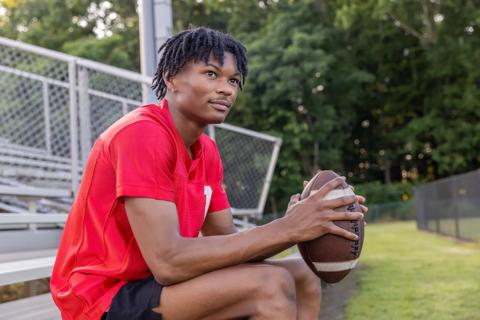 Boy sitting on bleachers while holding a football