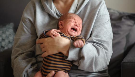 Newborn baby crying in caregiver's arms