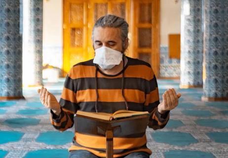 A man reading a book praying in a mosque