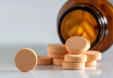 Circular orange pills spilling out of a tipped-over bottle