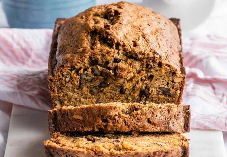 A fresh loaf of zucchini bread sits sliced on a decorative towel.